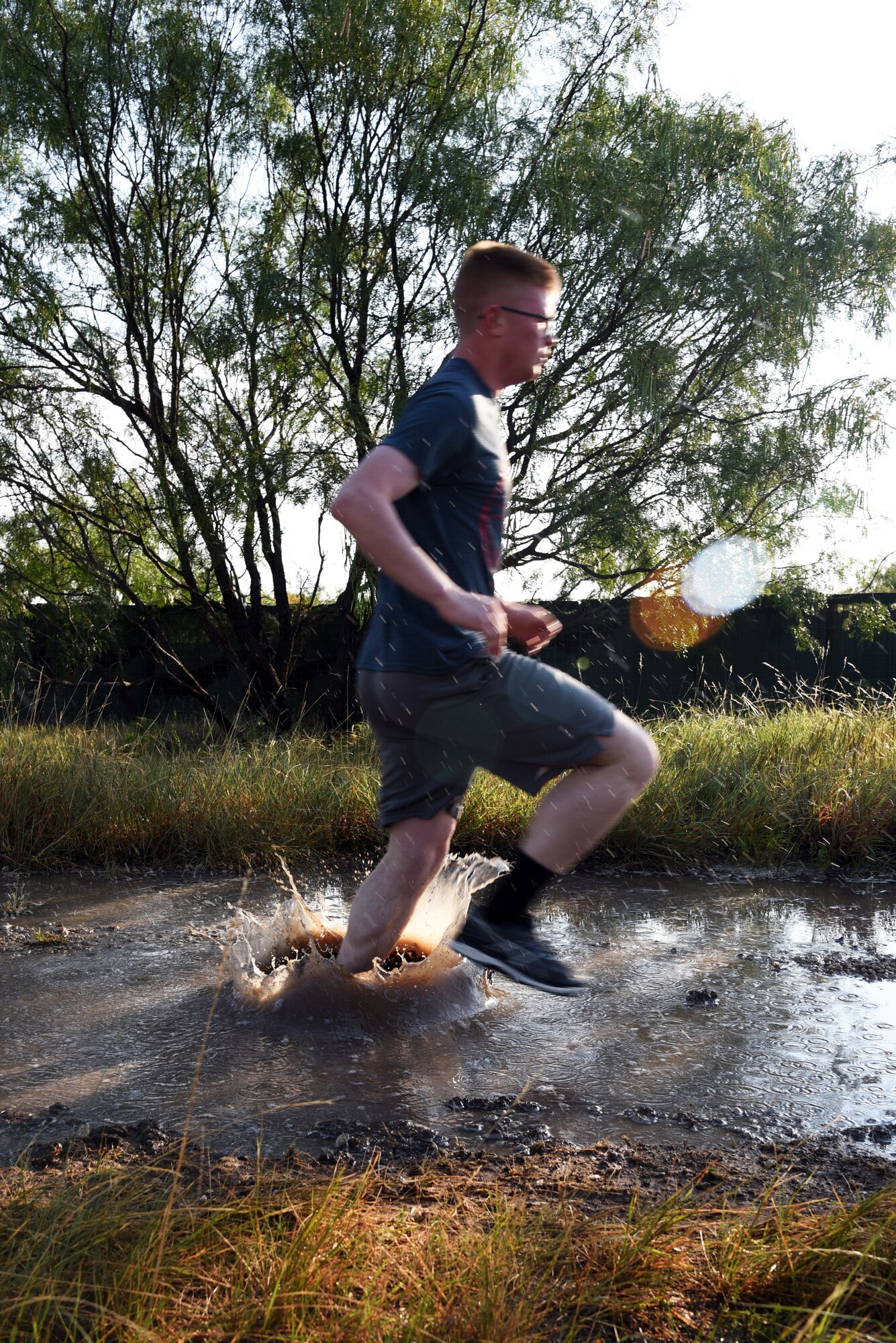 U.S. Army Pvt. Conner McCage, 344th Military Intelligence Battalion trainee, runs through a puddle during the 344th MI BN mud run at the Camp Sentinel training area on Goodfellow Air Force Base, Texas, July 7, 2018. Besides running through puddles, participants in the mud run also had to jump barriers, climb a dirt hill and perform a low crawl. (U.S. Air Force photo by Staff Sgt. Joshua Edwards/Released)