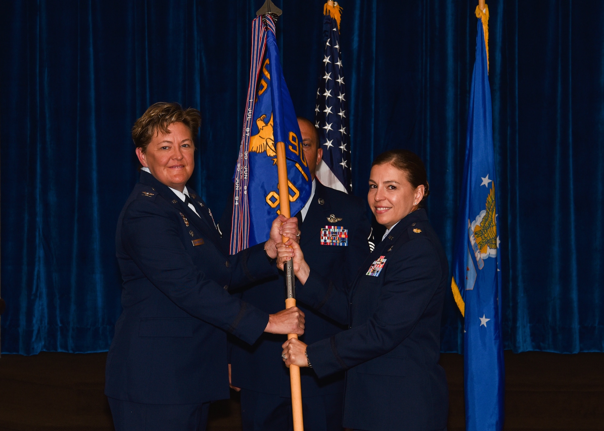 Colonel Tricia Van Den Top, 90th Mission Support Group commander, passes the guidon to Maj. Isabella Ramirez, 90th Force Support Squadron commander, during the 90th FSS change of command ceremony July 9, 2018, on F.E. Warren Air Force Base, Wyo. The ceremony signified the transition of command from Lt. Col. Shannon Hughes. (U.S. Air Force photo by Airman 1st Class Braydon Williams)