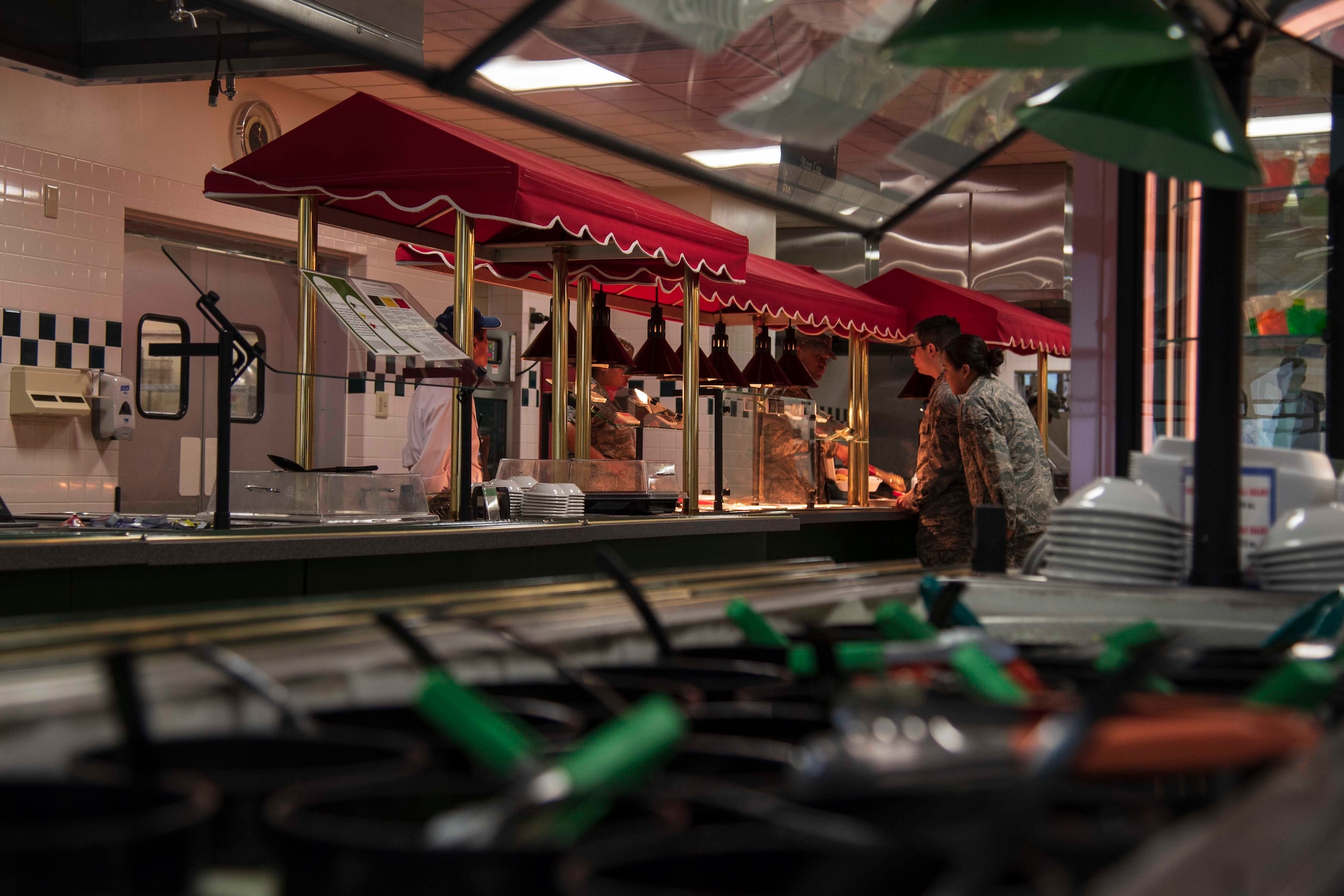 A Grissom Dining Facility food service specialist serves two Airmen at Misawa Air Base, Japan, July 5, 2018. In 2017, the Grissom Dining Facility achieved the highest score for healthy food options on Misawa AB through the Military Nutrition Environment Assessment Tool, which assesses the availability of nutritious foods such as vegetables, low fat and low sodium items. (U.S. Air Force photo by Airman 1st Class Collette Brooks)