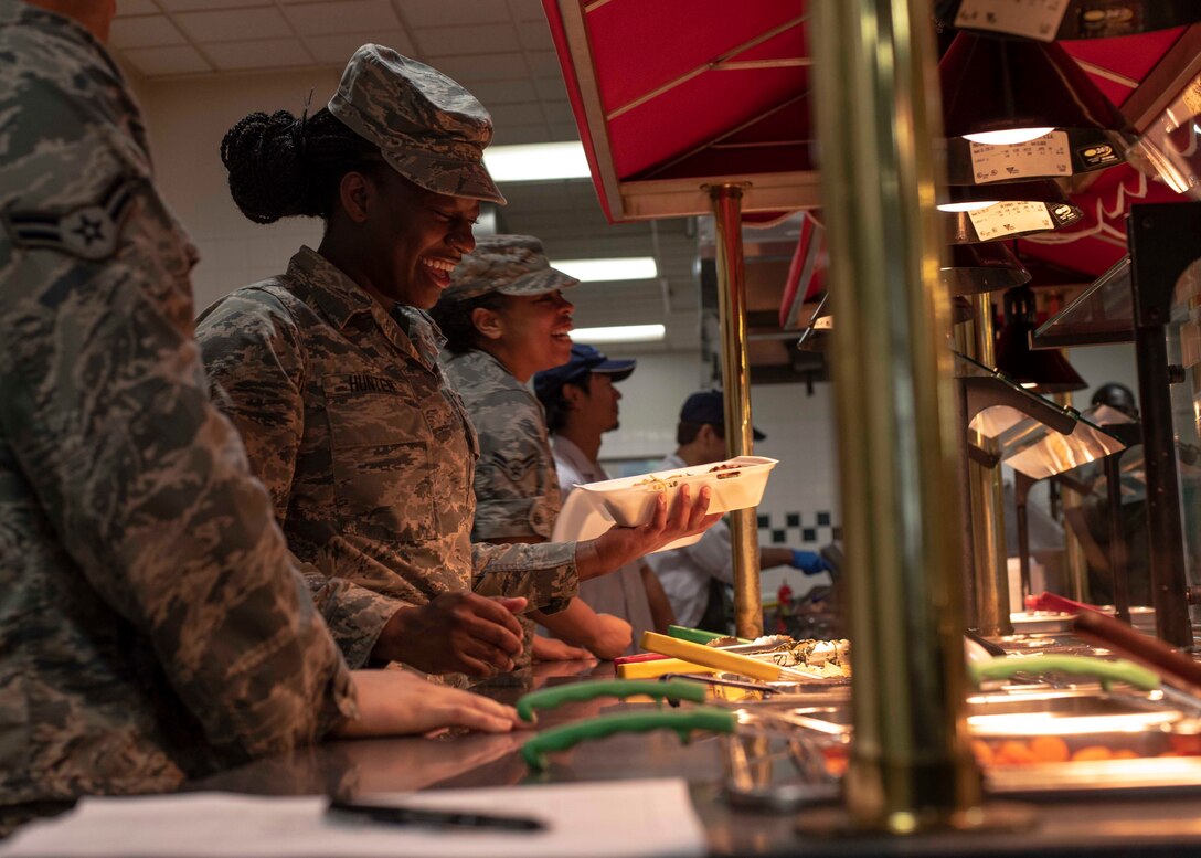 U.S. Air Force Airman Anaya Hunter, a 35th Force Support Squadron food service apprentice, smiles while serving a guest at the Grissom Dining Facility at Misawa Air Base, Japan, July 5, 2018. The facility provides Team Misawa members with a supportive environment in order to enhance healthy eating practices, prevent weight gain and other diseases, which allows individuals to meet mission requirements and maintain fitness for duty. (U.S. Air Force photo by Airman 1st Class Collette Brooks)