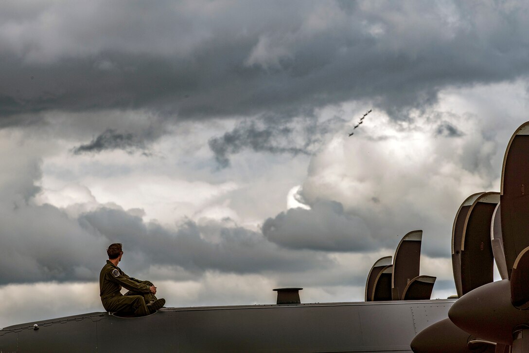 A pilot sits on top of an aircraft while watching an aircraft performance.