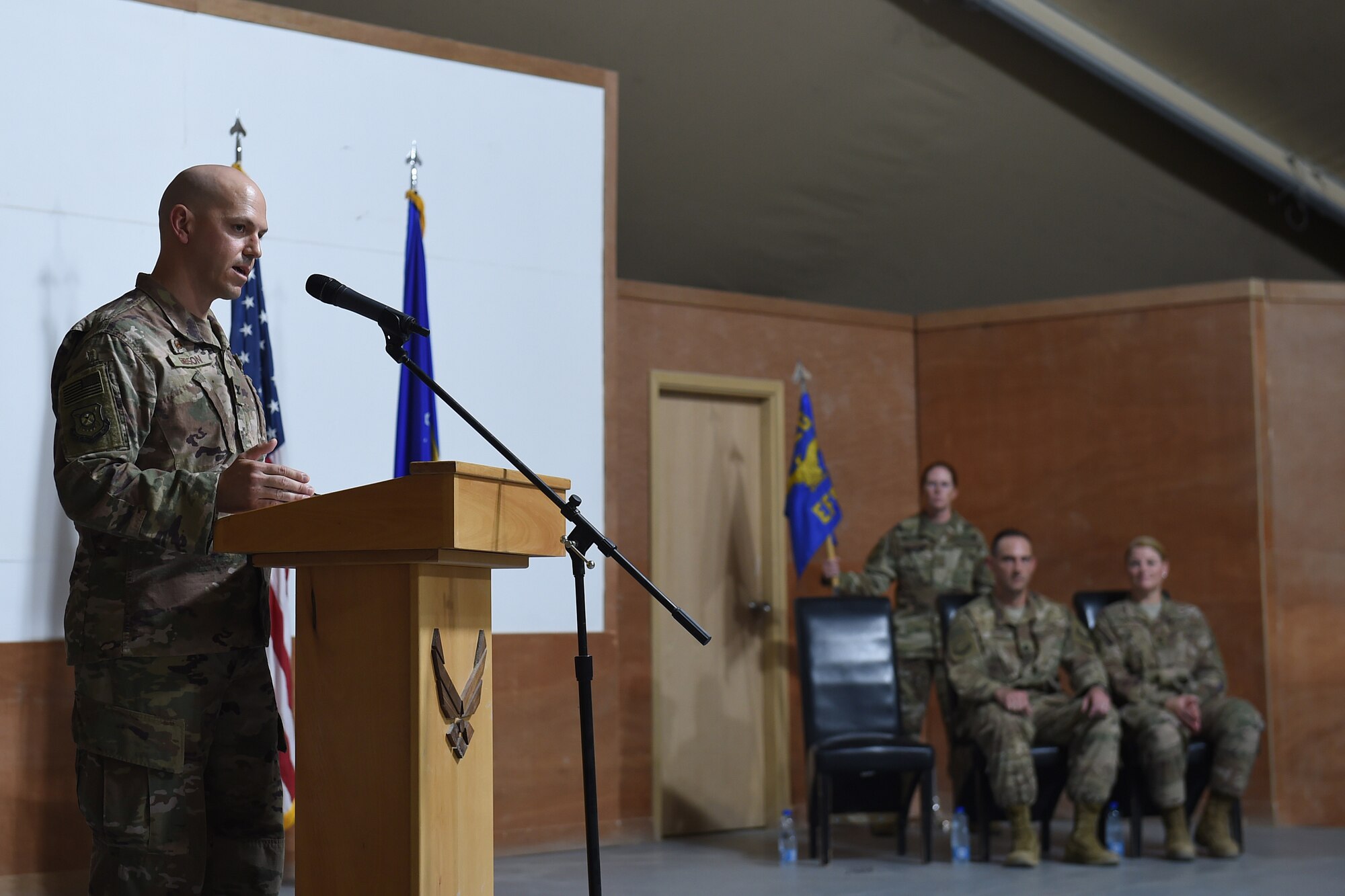 Airman stands behind podium to speak to audience.