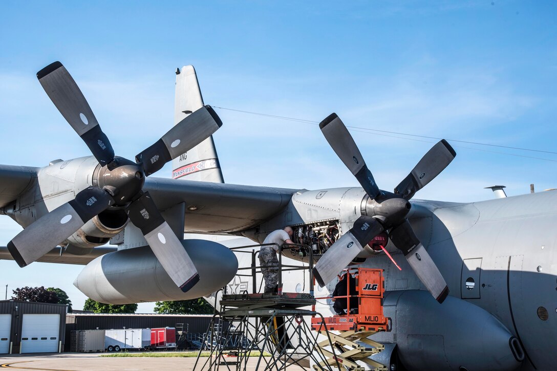 Airmen perform maintenance on the engine of a C-130H Hercules.