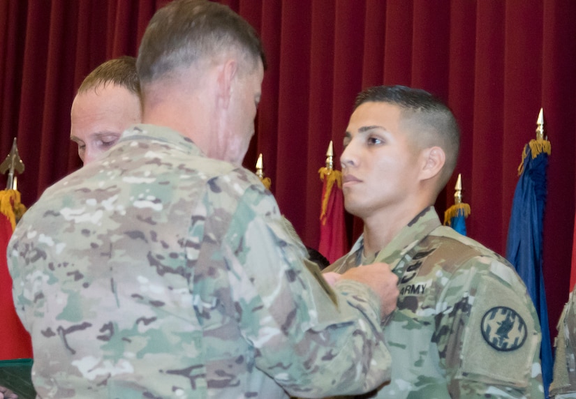 U.S. Army Maj. Gen. "Donnie" B. Walker, commanding general of the 1st Theater Sustainment Command, pins an Army Commendation Medal to the chest of U.S. Army Sgt. 1st Class Roberto Castaneda, a platoon sergeant with the 202nd Military Police Company attached to U.S. Army Central Personnel Security Detail as the noncommissioned officer in charge, at the Sergeant Audie Murphy Club induction ceremony held at Camp Arifjan, Kuwait, July 7, 2018. The ceremony was held to induct Castaneda and Sgt. 1st Class Jonah Even, a maintenance management noncommissioned officer assigned to the 401st Army Field Support Battalion-Qatar, into the SAMC.