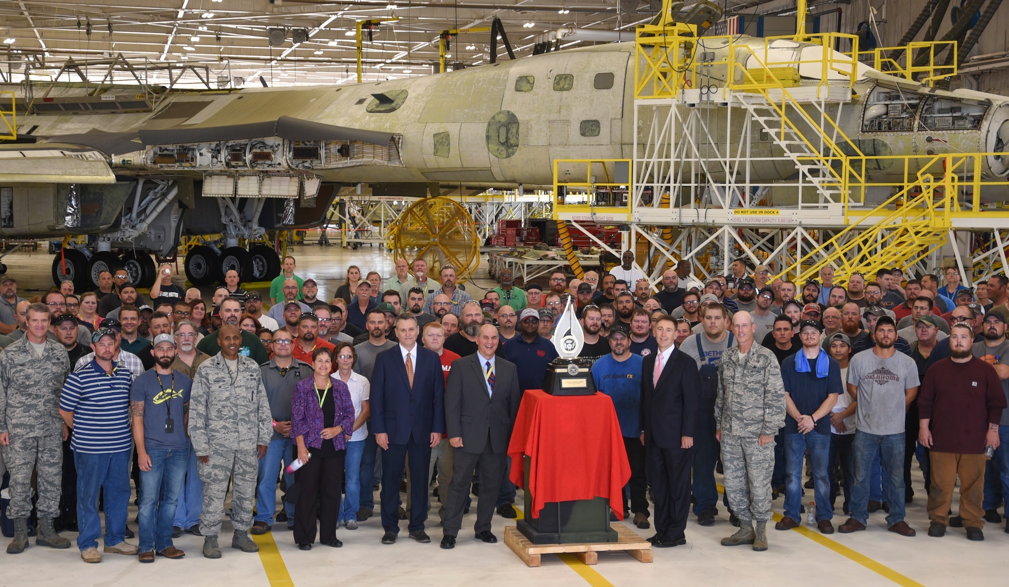 Senior leaders from the Department of Defense and Oklahoma City Air Logistics Complex stand near the Robert T. Mason trophy along with workers following the formal presention to the 567th Aircraft Maintenance Squadron on June 27, 2018, Tinker Air Force Base, Oklahoma. The 567th was recognized for their work on the ongoing B-1B Integrated Battle Station upgrades.