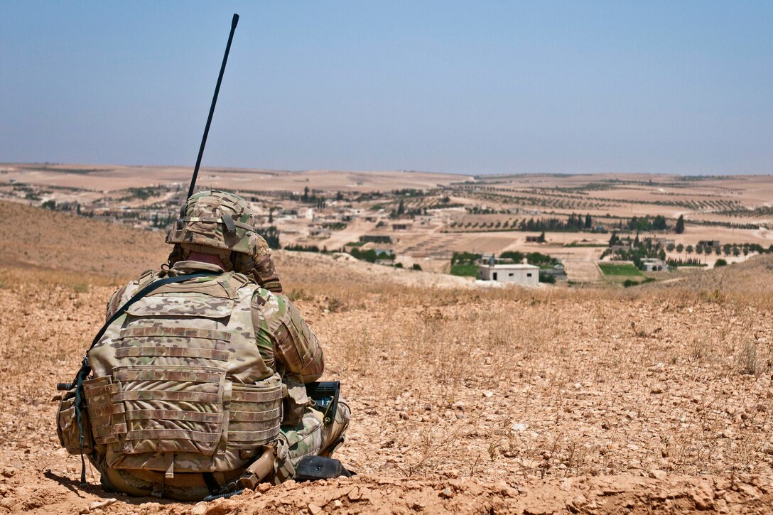 A U.S. soldier looks through binoculars to identify Turkish soldiers conducting a coordinated, independent patrol.