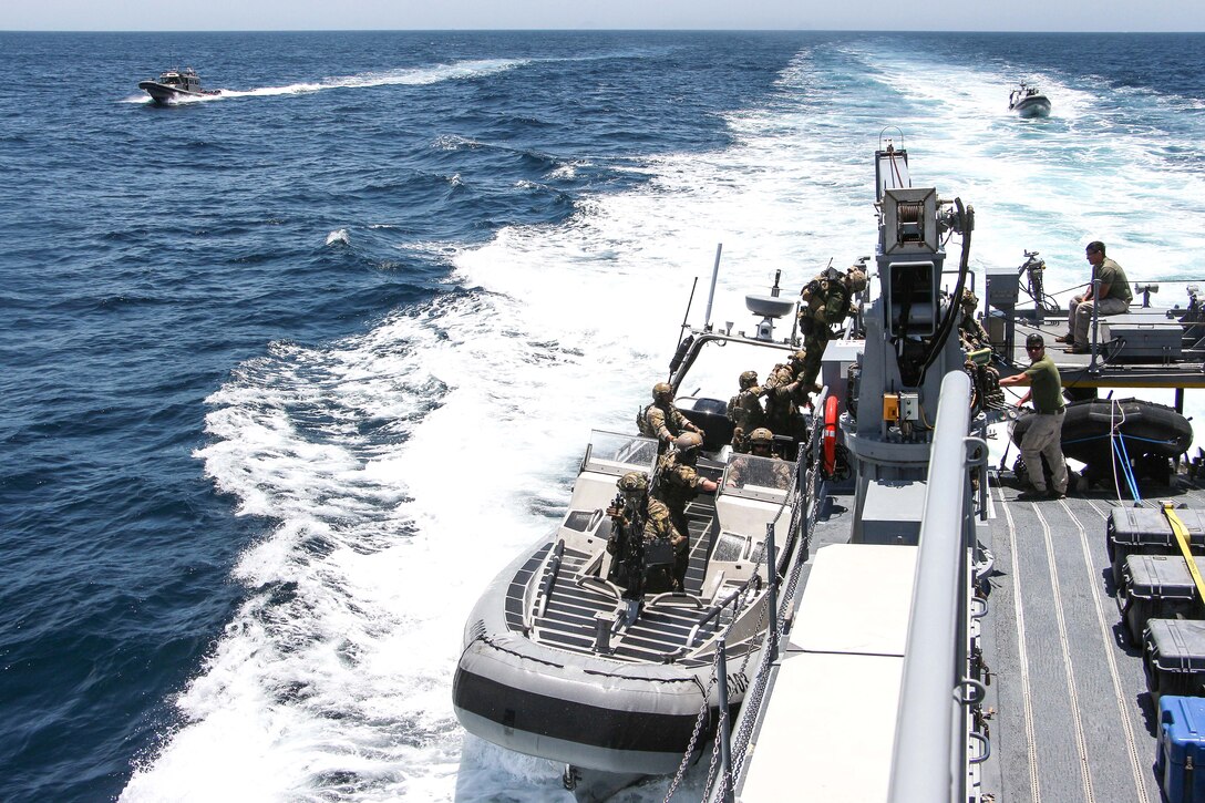 U.S. Coast Guard and Canadian sailors board a small high-speed boat.