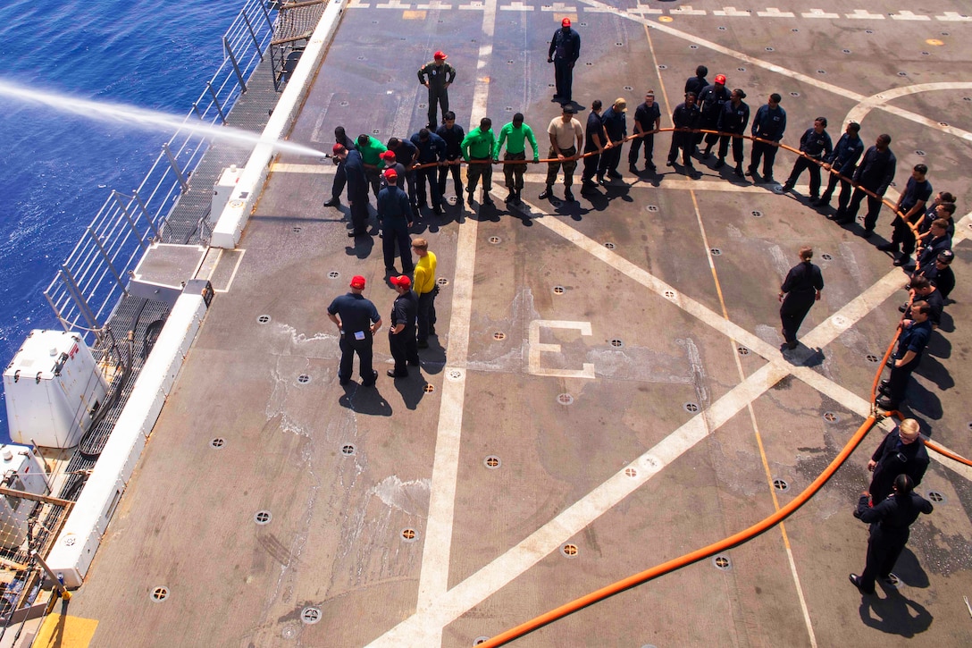 Navy sailors discharge a firehose during damage control training team drills.