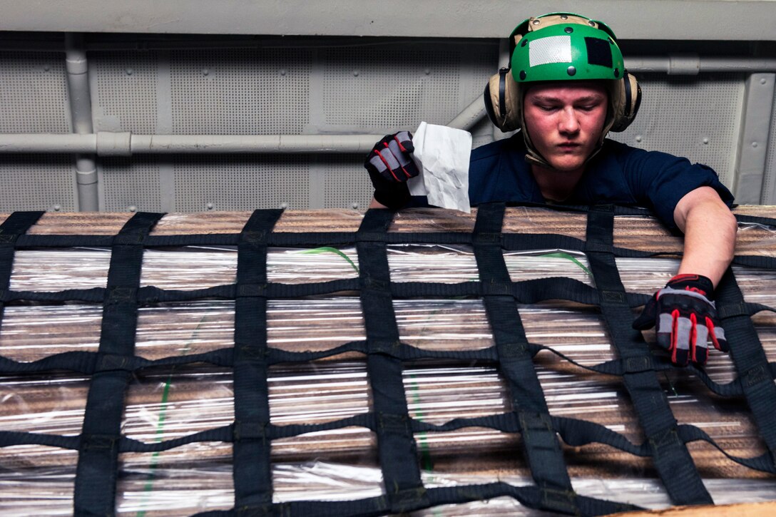 A seaman performs an inventory check in the hangar bay of the Nimitz-class aircraft carrier USS Carl Vinson.