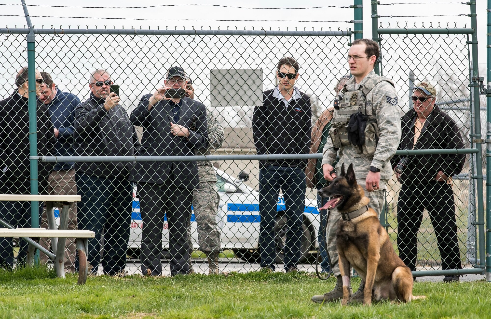 Karlo, a 436th Security Forces Squadron military working dog, sits next to Staff Sgt. David Bischoff, 436th SFS MWD handler during a training demonstration, April 11, 2018, at Dover Air Force Base, Del. Joey Logano, driver of the No. 22 Ford in the Monster Energy NASCAR Cup Series, watched Karlo, an 80-pound Belgian Malinois MWD, wait for the command to attack from Bischoff. (U.S. Air Force photo by Roland Balik)