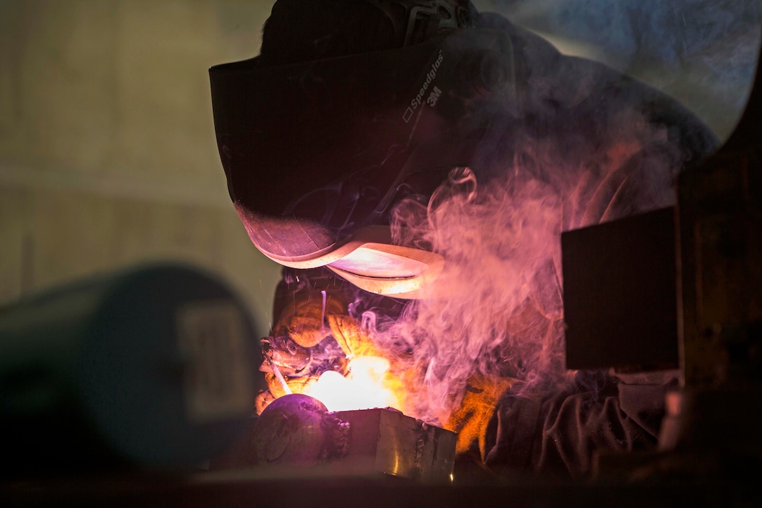 A man welds a piece of metal.