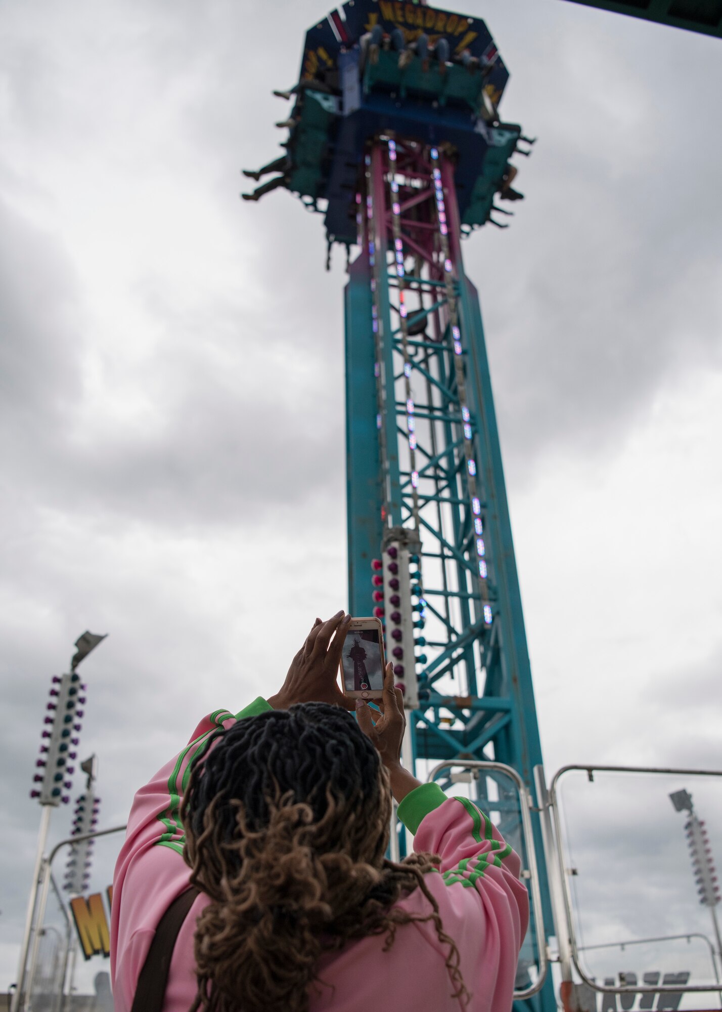 A spectator takes a picture of participants riding the “Mega Drop” during the 3rd annual Summer Fest hosted by the 673d Force Support Squadron at Joint Base Elmendorf-Richardson, Alaska, July 8, 2018. The event was open to anyone with base access and offered free activities such as carnival rides, a petting zoo, face painting, a bungee trampoline, and carnival games.