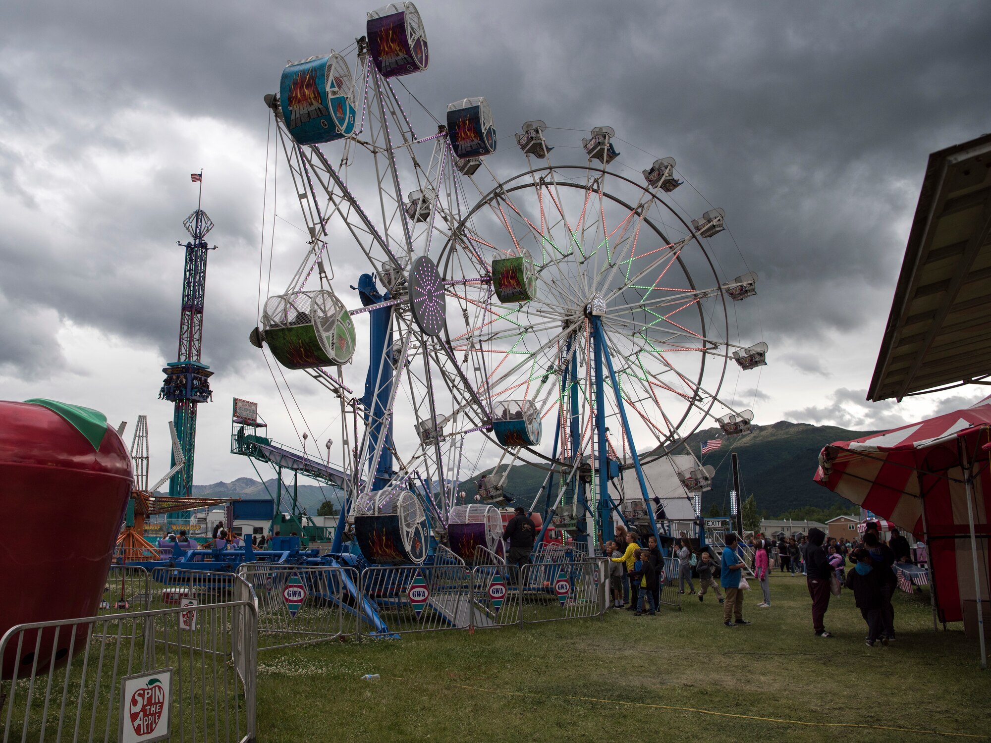 Participants wait in line for amusement rides and games offered during the 3rd annual Summer Fest hosted by the 673d Force Support Squadron at Joint Base Elmendorf-Richardson, Alaska, July 8, 2018. The event was open to anyone with base access and offered free activities such as carnival rides, a petting zoo, face painting, a bungee trampoline, and carnival games.