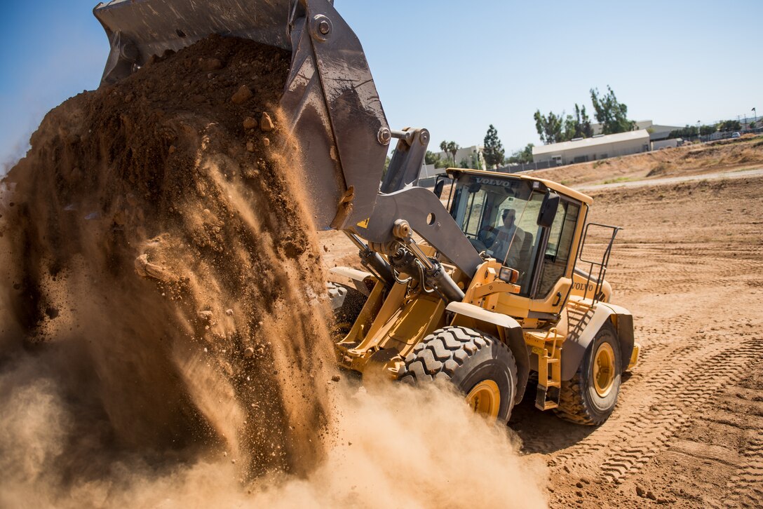 Airman 1st Class Kevin Coulter, a pavement and heavy equipment operator with the 137th Special Operations Civil Engineering Squadron (137th SOCES), Oklahoma City, dumps a scoop of dirt from a loader during deployment readiness training at March Air Reserve Base in Riverside County, California, June 26, 2018. The 137th SOCES members train at a regional training site every three years as a part of this deployment readiness training. (U.S. Air National Guard photo by Staff Sgt. Brigette Waltermire)
