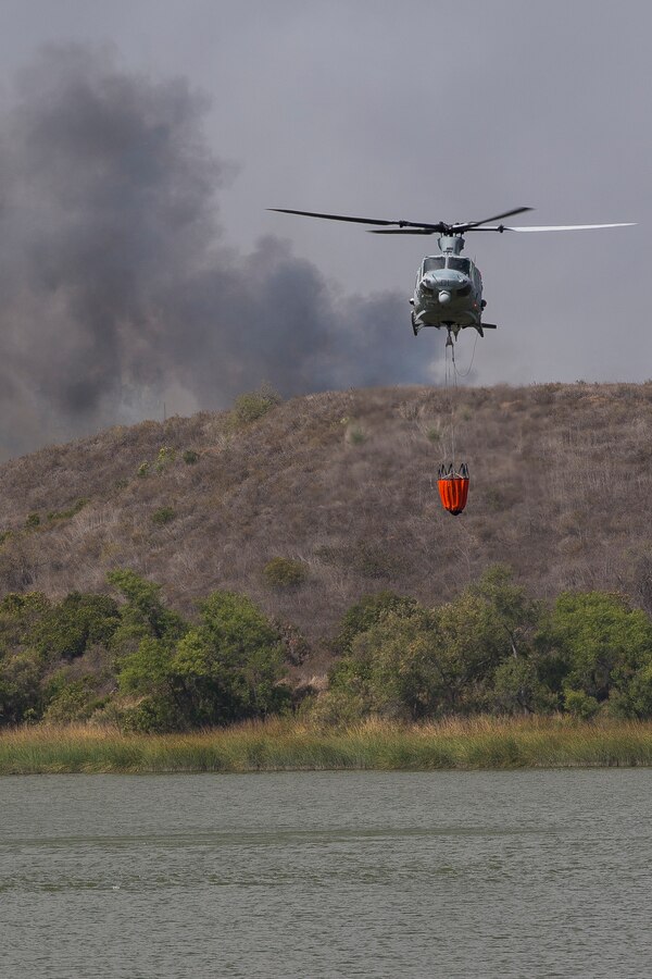 Marines with Marine Light Attack Helicopter Squadron 267, Marine Aircraft Group 39, retrieve water from Lake O'Neill to combat a fire in the Santa Margarita/De Luz housing area on Marine Corps Base Camp Pendleton, California, July 6, 2018.  (U.S. Marine Corps Photo by Cpl. Dylan Chagnon)