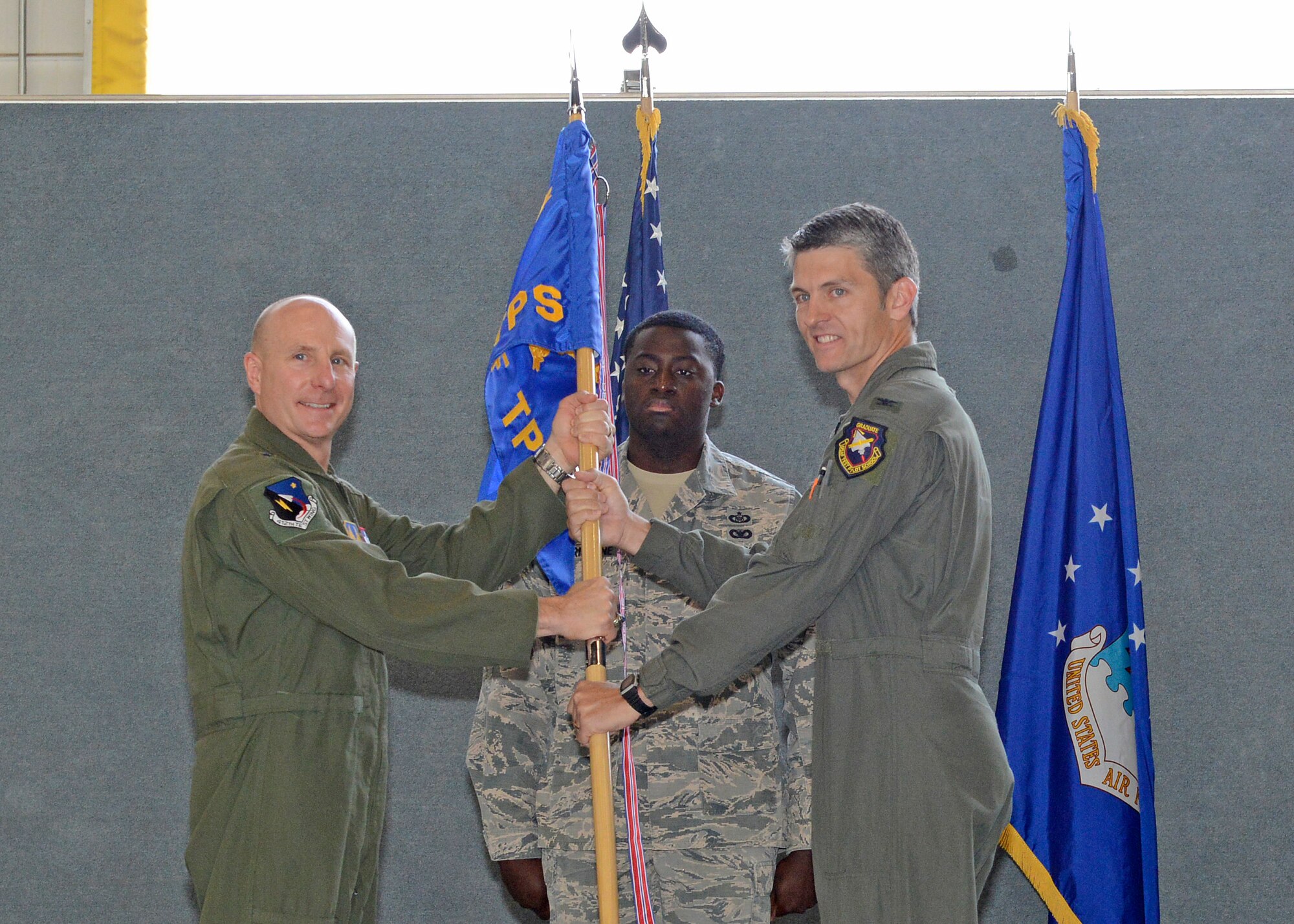 Brig. Gen. Carl Schaefer, 412th Test Wing commander (left), and new U.S. Air Force Test Pilot School commandant, Col. Ryan Blake, pose with the school’s guidon during a change of command ceremony in Hangar 1207 July 10. (U.S. Air Force photo by Kenji Thuloweit)