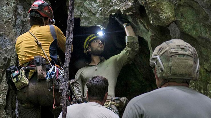 Four people work at the mouth of a cave.