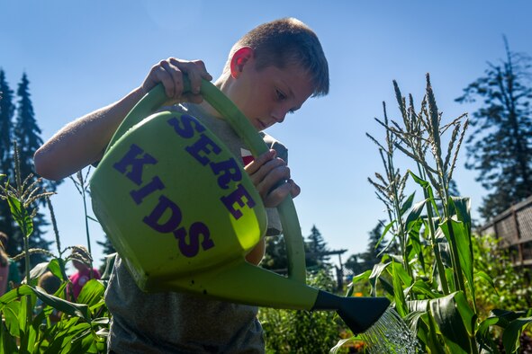Member of the Survival, Evasion, Resistance and Escape Kids’ Garden Club waters the rows of produce July 09, 2018 at Fairchild Air Force Base, Washington. Each family rotates on a weekly cycle, bringing their kids to grow, learn and make memories throughout the process. (U.S. Air Force photo/ Airman 1st Class Whitney Laine)