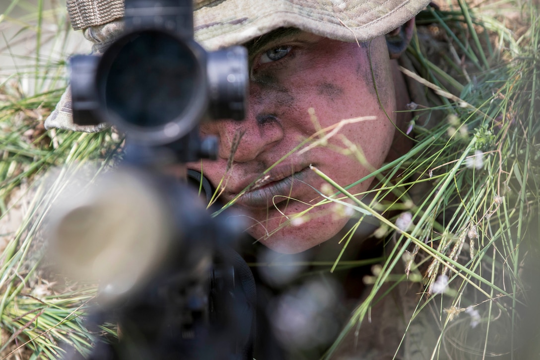 A soldier stares through a rifle scope.