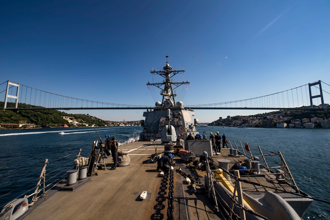 A ship travels toward a suspension bridge.