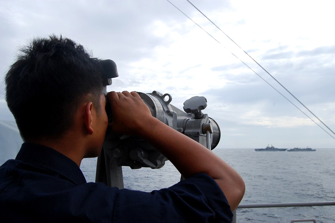 A sailor watches as the USS Kearsarge comes alongside the Military Sealift Command fast combat support ship USNS Supply.