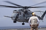 A U.S. Navy sailor watches as a CH-53E Super Stallion helicopter with Special Purpose Marine Air-Ground Task Force - Southern Command comes in for a landing on the flight deck of the USS Gunston Hall while conducting deck landing qualification training off the coast of Belize, July 7, 2018. The Marines of SPMAGTF-SC worked closely with Gunston Hall sailors to qualify six pilots and five enlisted aircrew members responsible for the helicopters’ safe operation. Having qualified Marines provides SPMAGTF-SC with helicopter movement capabilities of personnel and cargo between the shore and ship. The Marines and sailors of SPMAGTF-SC are conducting security cooperation training and engineering projects alongside partner nation military forces in Central and South America. The unit is also on standby to provide humanitarian assistance and disaster relief in the event of a hurricane or other emergency in the region.