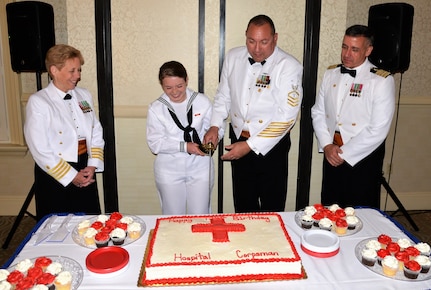 Navy Seaman Katlin Dowling, center left, a hospital apprentice serving at Naval Health Clinic Charleston, and NHCC Command Master Chief Anthony Petrone, center right, cut the cake during NHCC’s Hospital Corpsman Ball, celebrating the 120th birthday of the US Navy Hospital Corps. Standing by are NHCC Executive Officer Capt. Kathleen Hinz, far left, and NHCC Commanding Officer Capt. Dale Barrette, far right.
