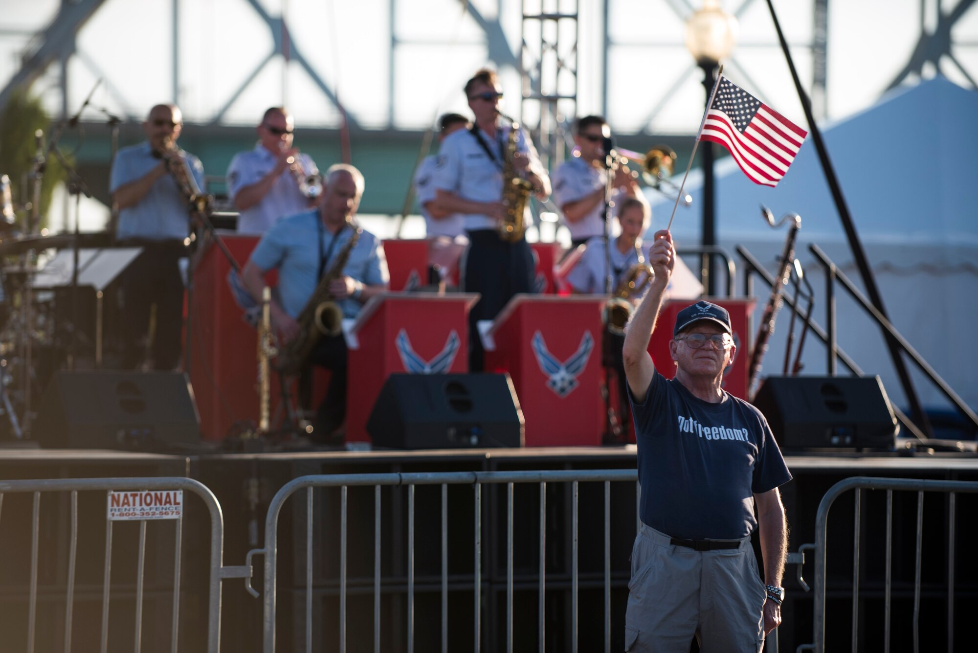 Man holding flag in front of stage where Jazz ensemble is  playing