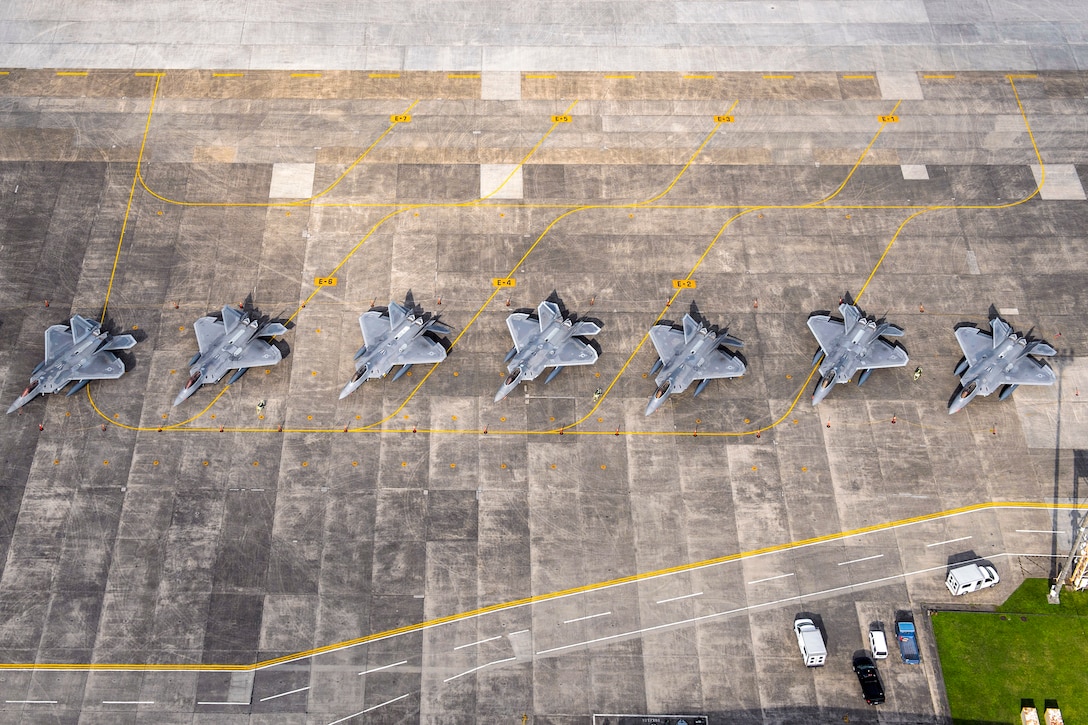 A line of aircraft sit on a flat surface..