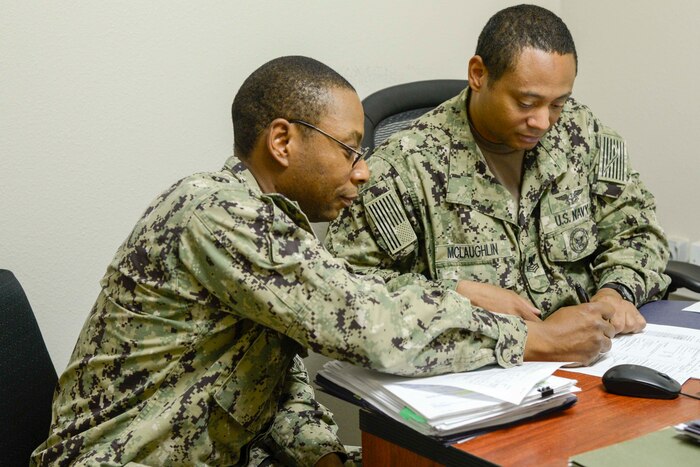 Sailors discuss the Reserve Component to Active Component  program at a desk.
