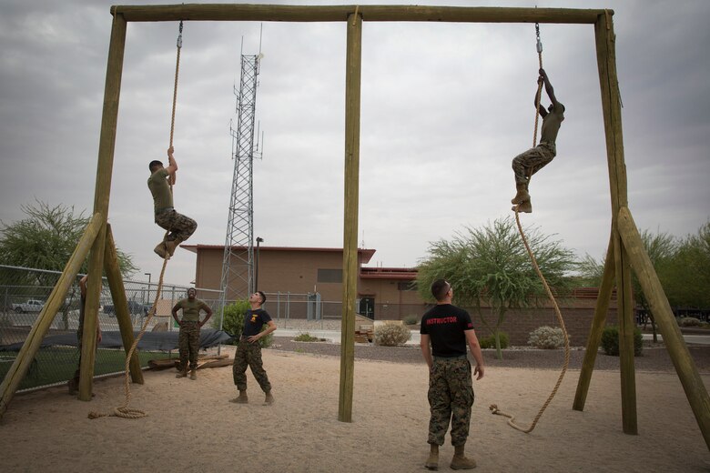 U.S. Marine Corps Sgt. Jesse Clay, and Sgt. Alberto Deloreyes, instructors with Corporals Course class 6-18, Marine Corps Air Station (MCAS) Yuma, Ariz., motivate students as they conduct an obstacle course on MCAS Yuma, Ariz., June 15, 2018. Marines, Sailors and Airmen attended the two week course focused on Marine Corps leadership, standards, professional development and physical fitness. (U.S. Marine Corps photo by Sgt. Allison Lotz)