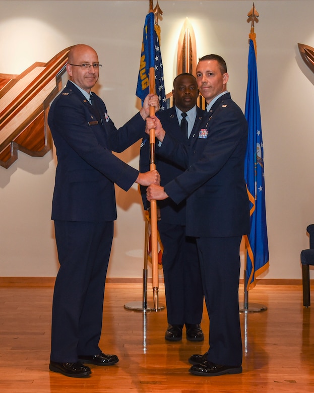 U.S. Air Force Col. Scott McKim, 325th Medical Group commander (left), passes the ceremonial guidon to Lt. Col. Michael Frayser, incoming 325th Aerospace Medicine Squadron commander (right), during a change of command ceremony at Tyndall Air Force Base, Fla., July 9, 2018.