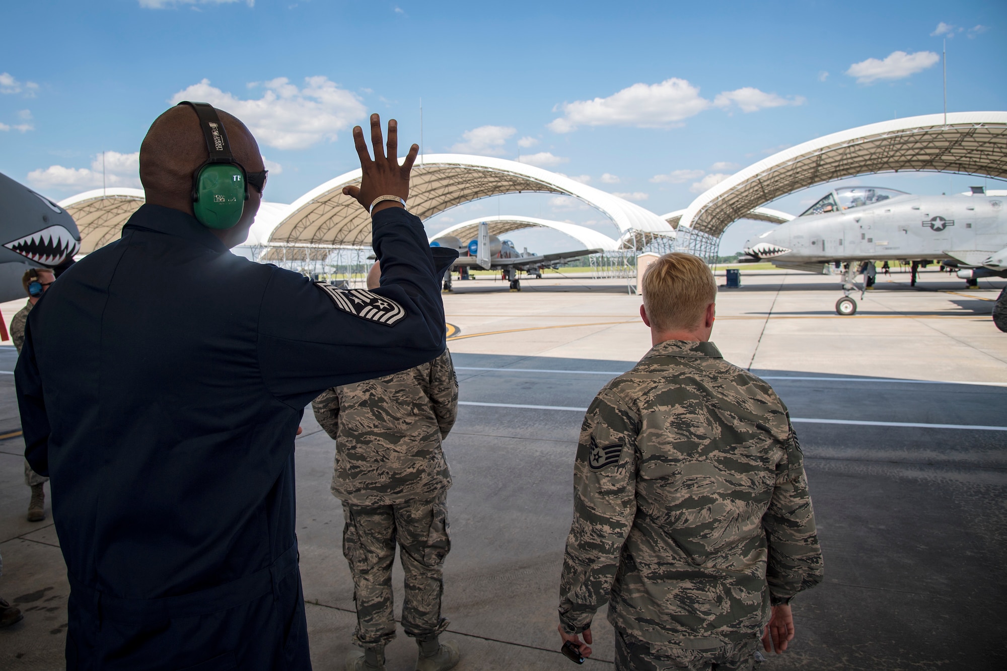 Chief Master Sgt. James Allen, 23d Wing command chief, rear, waves at an A-10C Thunderbolt II pilot during an immersion tour, July 10, 2018, at Moody Air Force Base, Ga. Allen toured the 23d Aircraft Maintenance Squadron (AMXS) to build rapport and experience the day to day operations of maintenance Airmen. Throughout his visit, Allen was able to speak with Airmen and hear their opinions and ideas behind the continued success of the AMXS. (U.S. Air Force photo by Airman 1st Class Eugene Oliver)