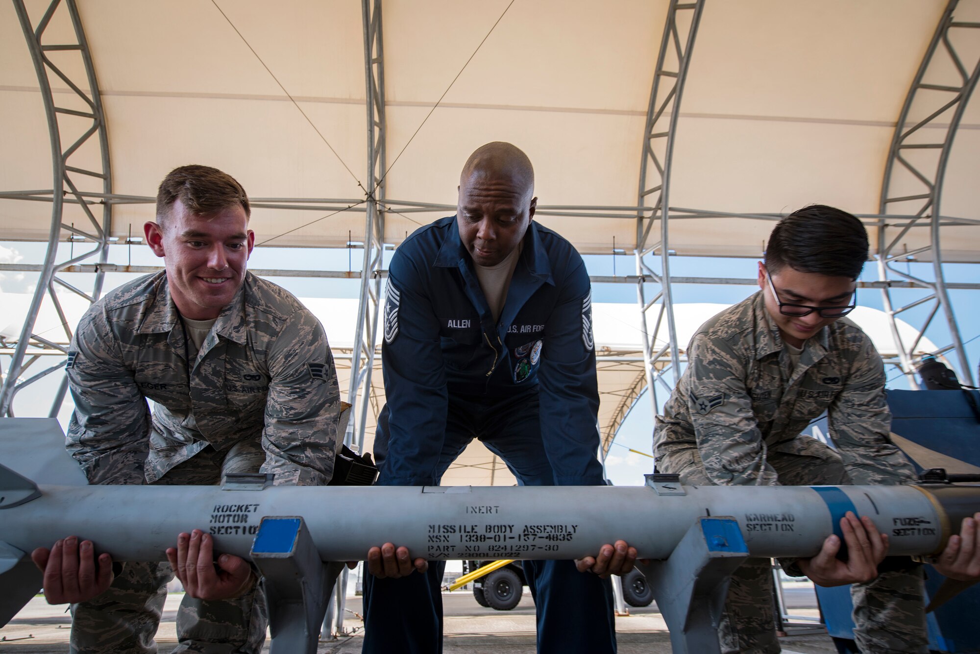 Chief Master Sgt. James Allen, 23d Wing command chief, center, and Airmen from the 23d Aircraft Maintenance Squadron (AMXS), lift an inert AIM-9 air-to-air missile during an immersion tour, July 10, 2018, at Moody Air Force Base, Ga. Allen toured the 23d AMXS to build rapport and experience the day to day operations of maintenance Airmen. Throughout his visit, Allen was able to speak with Airmen and hear their opinions and ideas behind the continued success of the AMXS. (U.S. Air Force photo by Airman 1st Class Eugene Oliver)