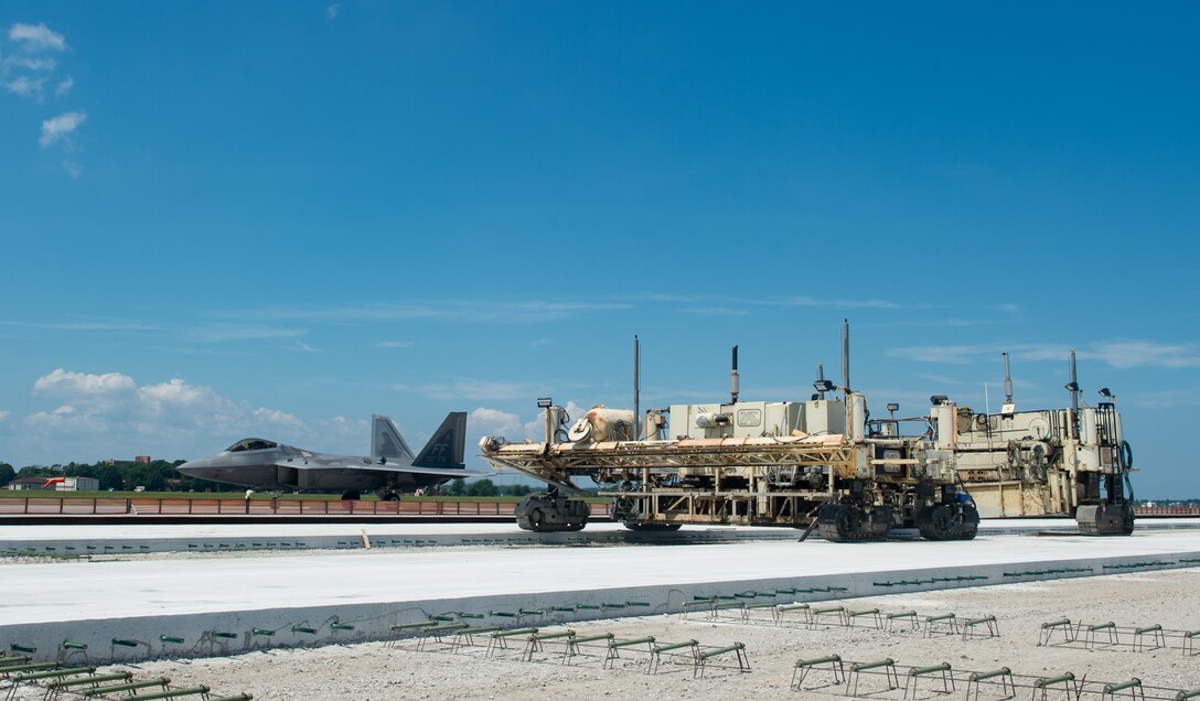 A U.S. Air Force F-22 Raptor assigned to the 1st Fighter Wing taxis past the slip form paver at Joint Base Langley-Eustis, Virginia, June 29, 2018. The Brownie Pad on the Langley Air Force Base flightline, is receiving a 48,000-square-yard upgrade, as part of an $11 million, three-phase project and will be called the “East Ramp,” upon completion of the 10-month construction in October 2018. (U.S. Air Force photo by Staff Sgt. Carlin Leslie)