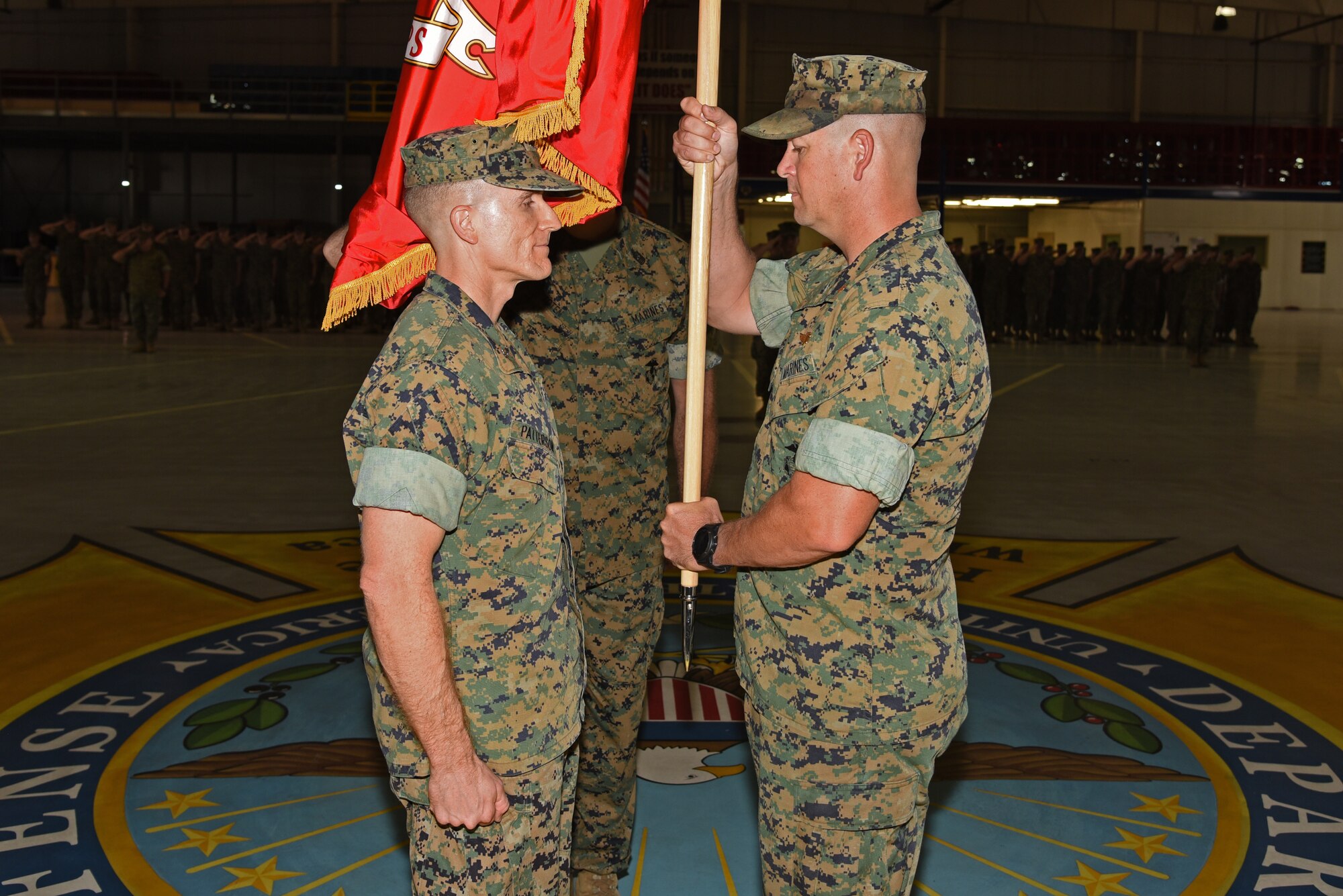 U.S. Marine Corps Maj. Andrew Armstrong, Marine Corps Detachment Goodfellow outgoing commanding officer, prepares to pass the guideon to Lt. Col. Earl Patterson, Marine Corps Detachment Goodfellow incoming commanding officer, during the Marine Corps Detachment Goodfellow Change of Command at the Louis F. Garland Department of Defense Fire Academy on Goodfellow Air Force Base, Texas, July 10, 2018. While holding the guideon, Armstrong received verbal orders to his next duty station before handling it to the incoming commander. (U.S. Air Force photo by Staff Sgt. Joshua Edwards/Released)