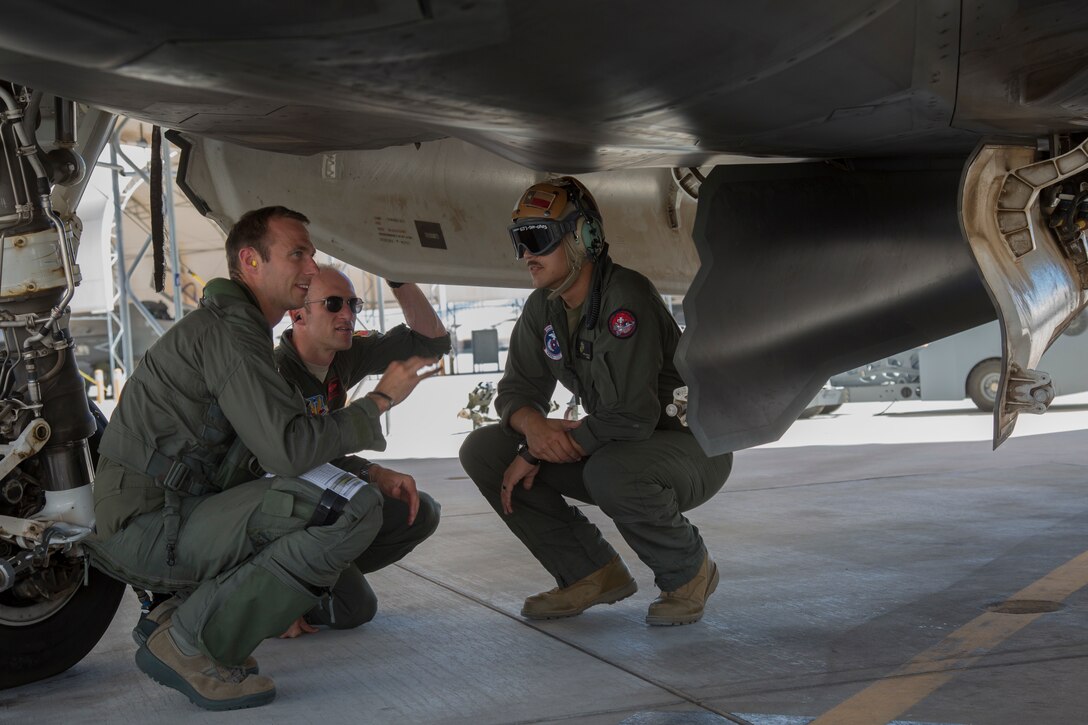 U.S. Airmen Capt. Timothy "Check" Six and Capt. Timothy "Check" Six, pilots, attached to Hill Air Force Base, Utah, discuss upcoming exercises with U.S. Marine Corps Staff Sgt. Richard R. Wharton, an aviation ordnance technicians with Marine Fighter Attack Squadron (VMFA) 122, Marine Corps Air Station (MCAS) Yuma, on MCAS Yuma, Ariz., June 26, 2018. The exercise tested, for the first time, the interoperability of loading weapon systems between the services F-35's. The U.S. Air Force operates with the F-35A Lightning II, while the U.S. Marine Corps operates with the F-35B Lightning II. (U.S. Marine Corps photo by Sgt. Allison Lotz)