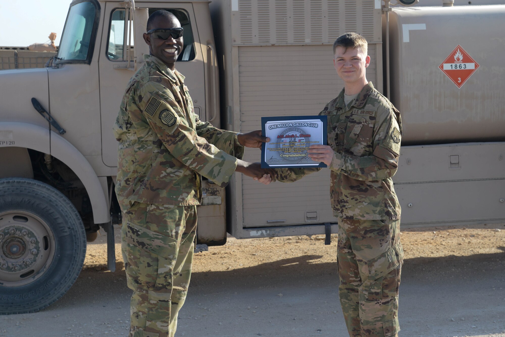 Lt. Col. Jamaal Mays, 332nd Expeditionary Logistics Readiness Squadron commander, presents the million gallon pumper certificate to Airman 1st Class Jacob Clonts at an undisclosed location in Southwest Asia, July 6, 2018.