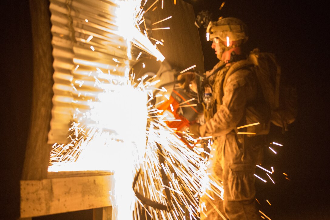 A U.S. Marine with 3rd Battalion 7th Marine Regiment attached to Special Purpose Marine Air-Ground Task Force, Crisis Response-Central Command cuts through a simulated aircraft cockpit during a tactical recovery of aircraft and personnel exercise July 9, 2018. The exercise simulated the rescue of two downed pilots in a night-time environment.