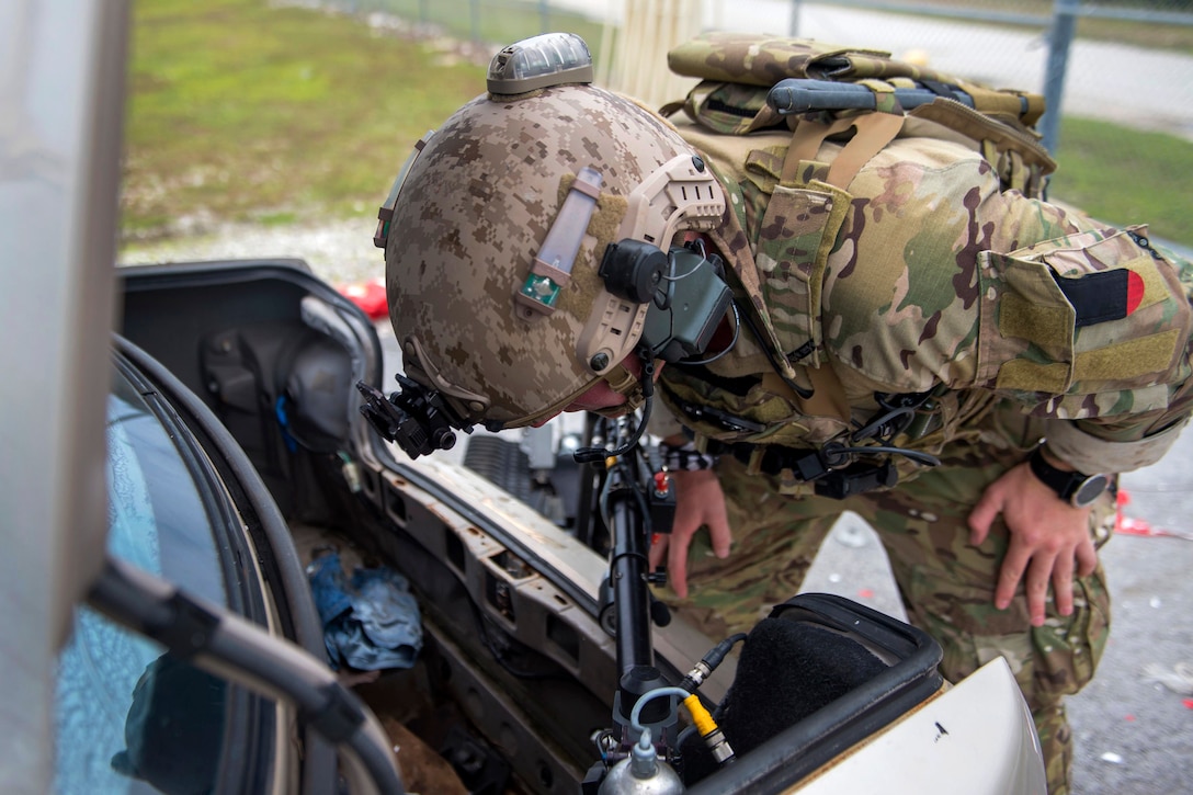 A sailor inspects a vehicle during an explosive ordnance disposal training exercise.