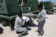 Two Airmen inspect a piece of equipment.