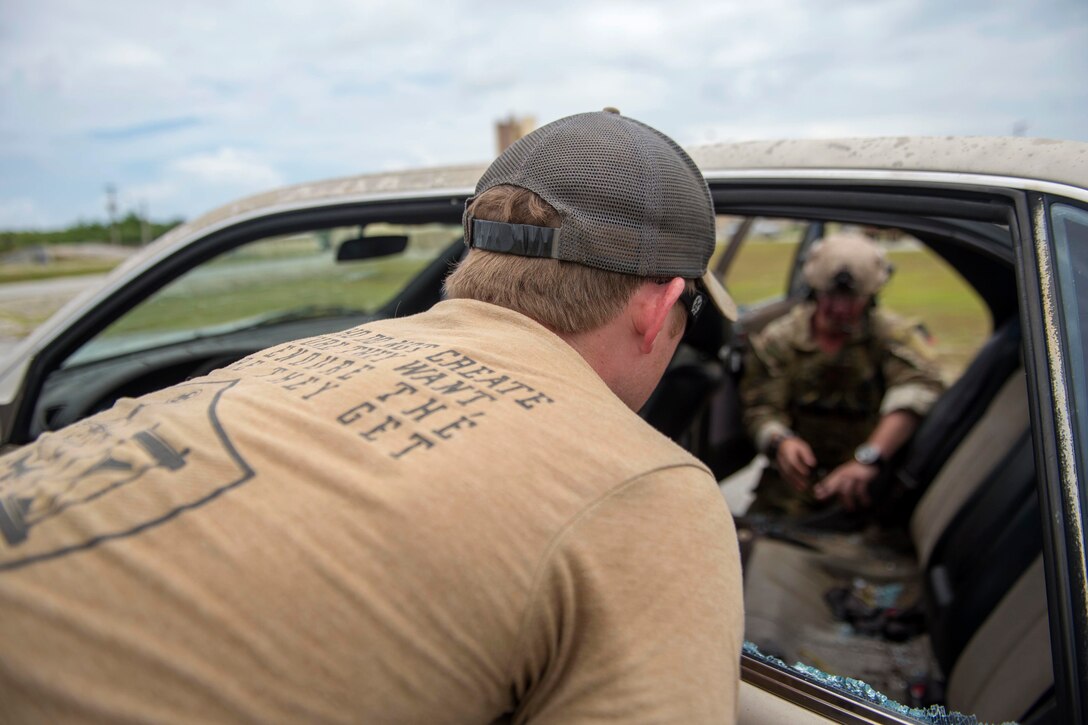 A sailor observes another sailor inspecting a vehicle during an explosive ordnance disposal training exercise.
