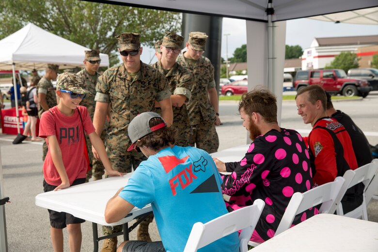 Service members and their families receive autographs from freestyle motocross performers during the exposition portion of a Semper Ride event on Marine Corps Base Camp Lejeune, June 26. Educating service members on the correct way to ride a motorcycle is the main mission of Semper Ride gatherings. (U.S. Marine Corps photo by Lance Cpl. Nathan Reyes)
