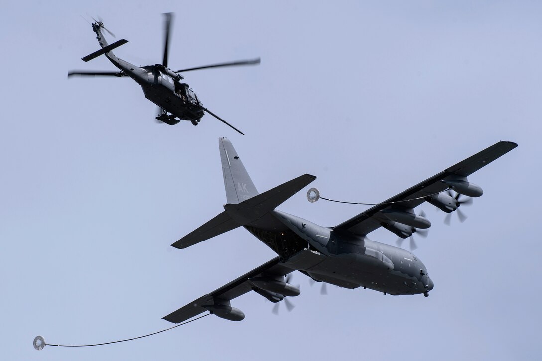 An HH-60G Pave Hawk helicopter and HC-130J Combat King II perform refueling operation.