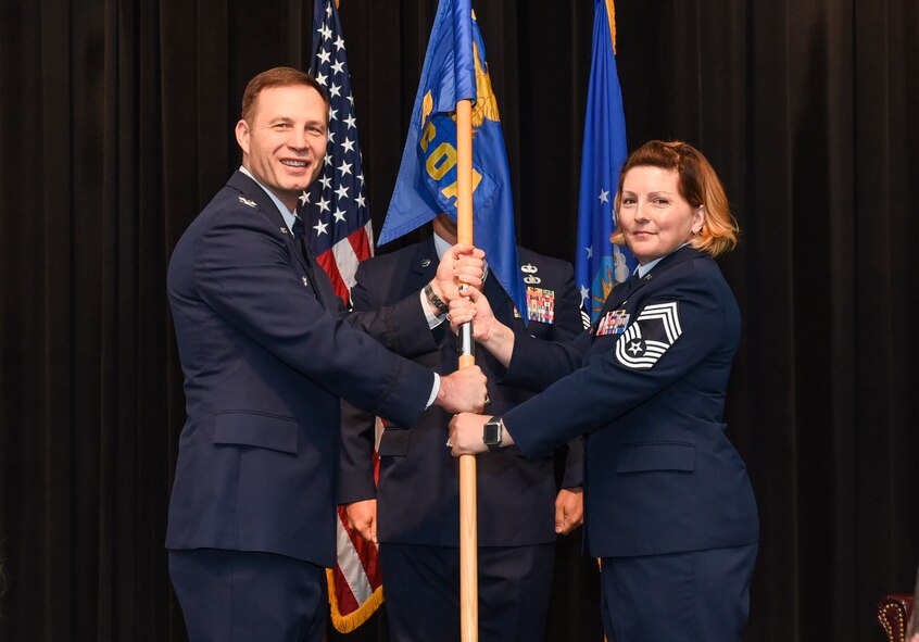 U.S. Air Force Col. James Dryjanski, Thomas N. Barnes Center for Enlisted Education commander and Air Command and Staff College commandant (left), passes the ceremonial guidon to Chief Master Sgt. Kristi Binard, incoming Paul W. Airey NCO Academy commandant (right), during an assumption of leadership ceremony at Tyndall Air Force Base, Fla., July 10, 2018.