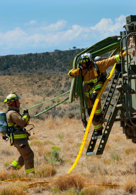 Soldiers off-load fire hoses from a tactical fire truck before conducting firefighting training.