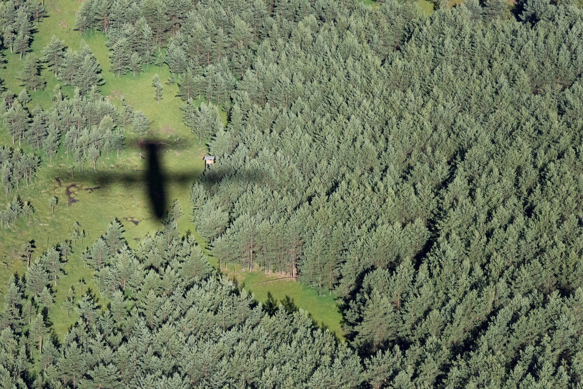 The shadow of a C-130J Super Hercules flies over the dense woods of Germany, July 2, 2018. This particular C-130J led the formation during an exercise that involved four other C-130Js. Once the pilots have led a formation long enough, they are recognized as multi-element flight lead qualified pilots. Multi-element flight lead qualified pilots help ensure the 37th Airlift Squadron is prepared to accomplish one of its primary missions: aerial delivery and mass on the drop-zone.