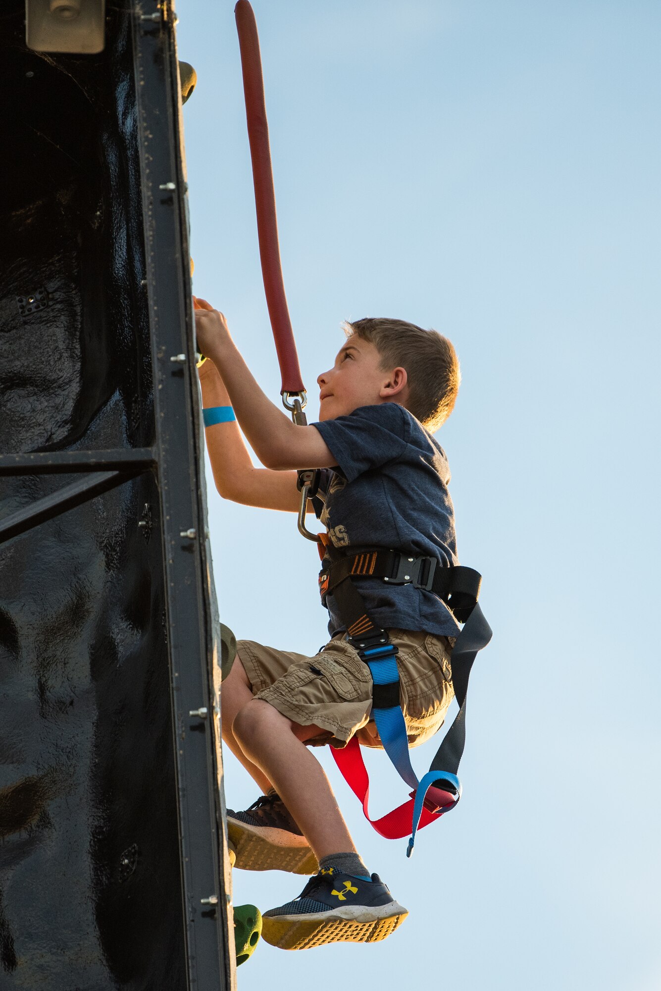 A child climbs up a rock wall prior to an Intel drone light show at Travis Air Force Base, Calif., July 5, 2018. The event featured numerous activities including music, bounce houses and an eight minute light show with 500 drones. (U.S. Air Force photo by Master Sgt. Joey Swafford)