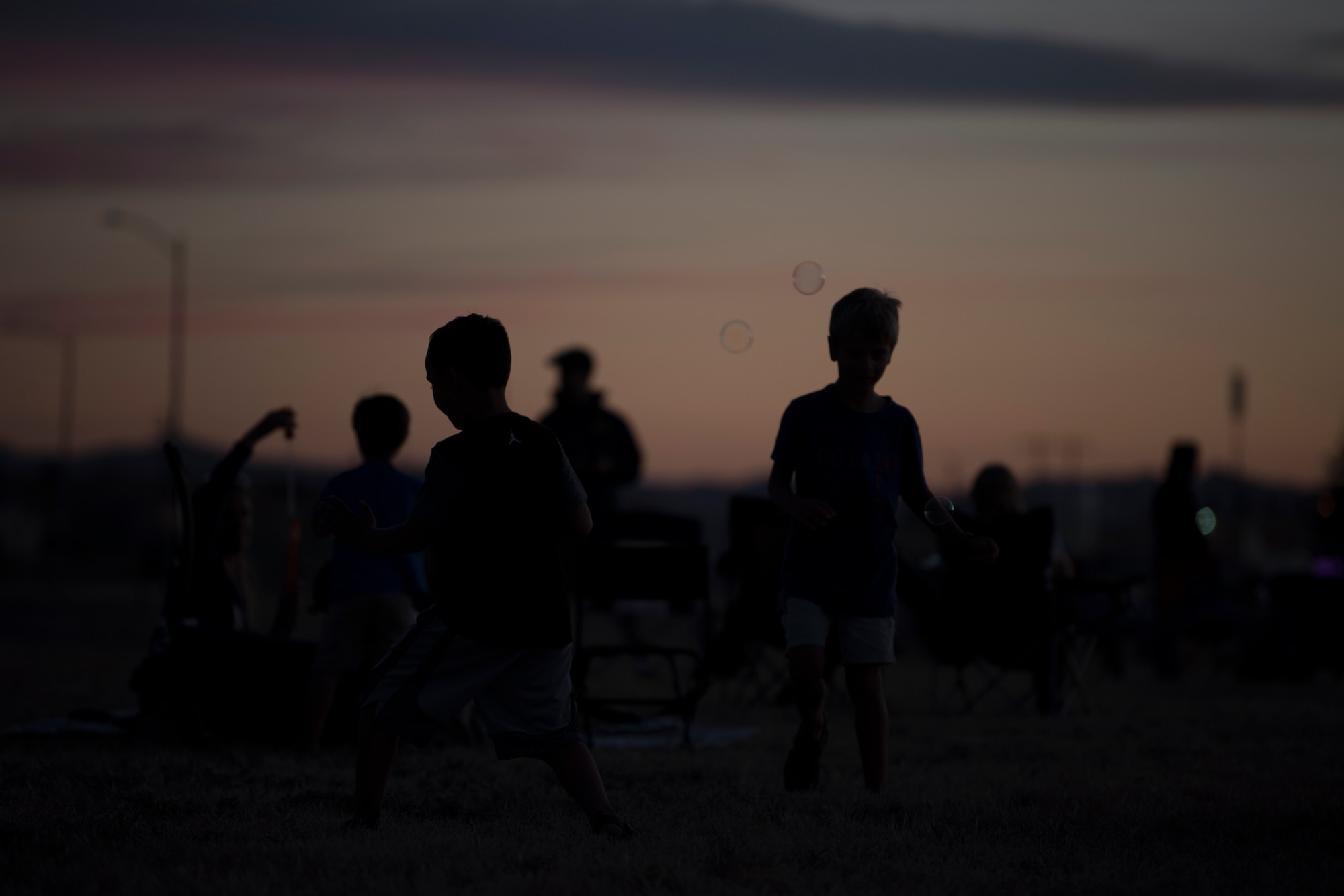 Children play with bubbles prior to an Intel drone light show at Travis Air Force Base, Calif., July 5, 2018. The event featured numerous activities including music, bounce houses and an eight minute light show with 500 drones. (U.S. Air Force photo by Tech. Sgt. James Hodgman)