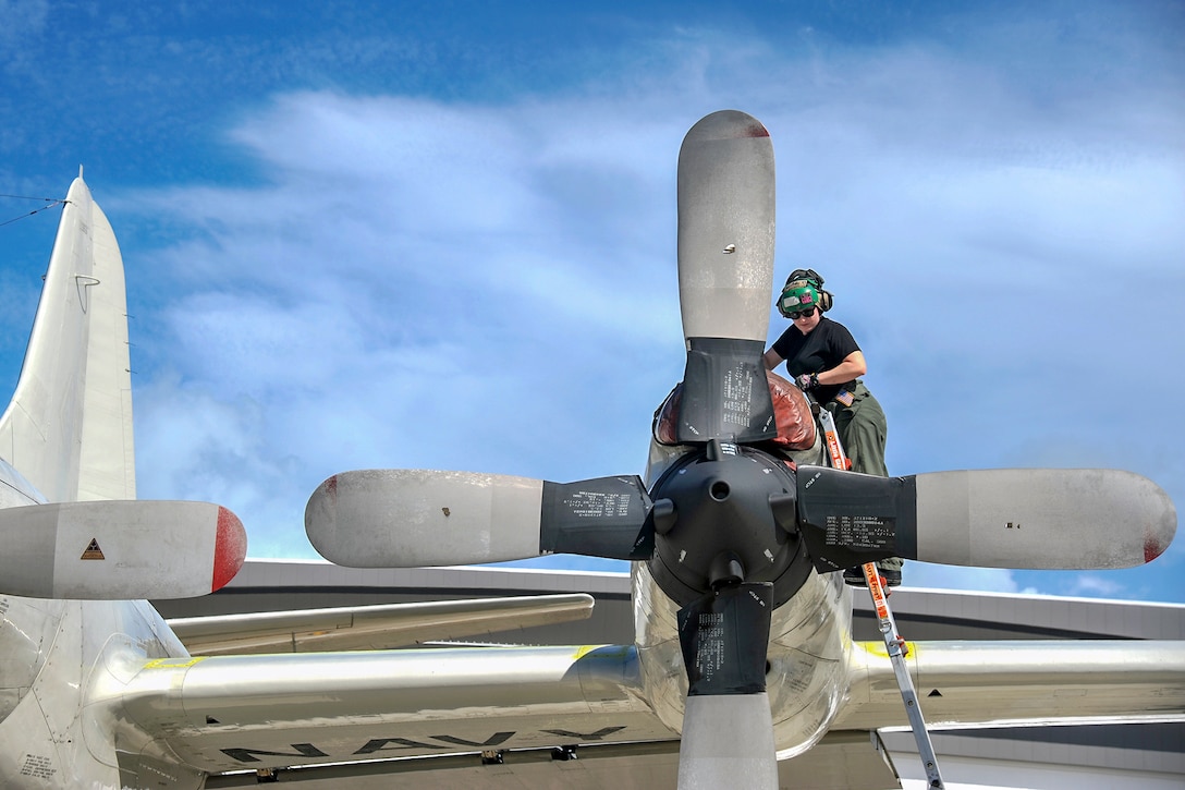 A sailor climbs a ladder onto an aircraft